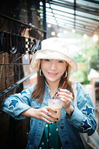 Portrait of smiling young woman having drink outdoors