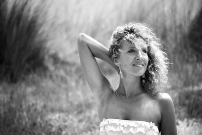 A young woman in a field holding her hair