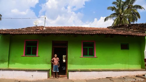 Woman standing by house against sky