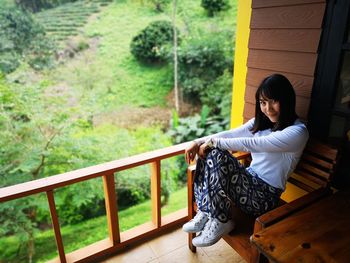 Portrait of smiling woman sitting on chair at balcony