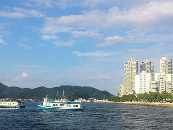 Boats sailing in sea against cloudy sky