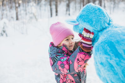 Father wearing costume with daughter on snowy field