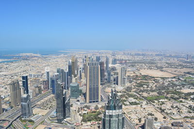 High angle view of modern buildings in city against clear blue sky