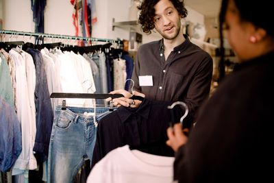 Salesman showing fashionable clothing to customer in store