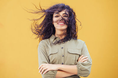 Portrait of smiling young woman against yellow background