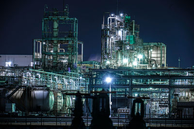 Illuminated factory against sky at night