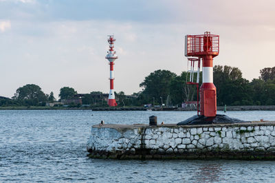 Lighthouse by river against sky