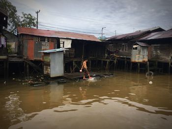 Man in water at town against sky