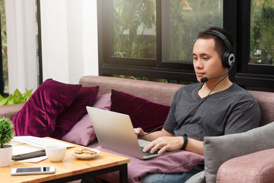 Young man using laptop while sitting on sofa