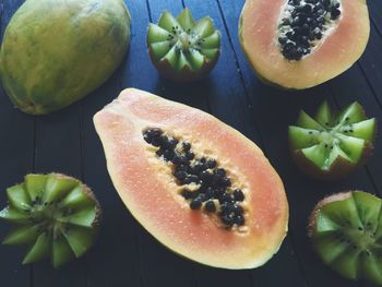 Close-up of halved papayas by kiwis on table