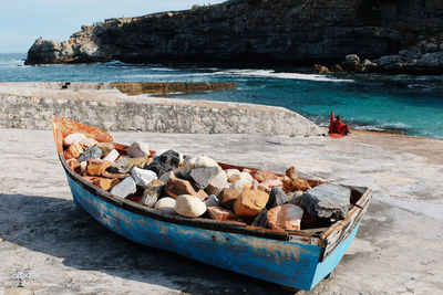 Boats on rocks by sea against sky