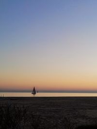 Silhouette of sailboat in sea at sunset