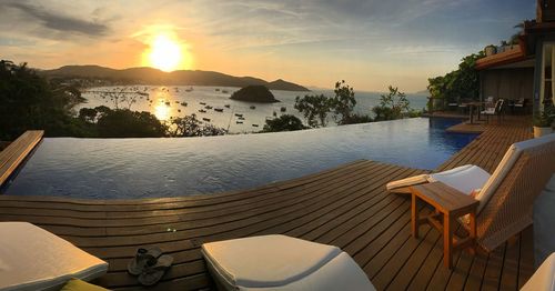 View of infinity pool by sea against sky during sunset