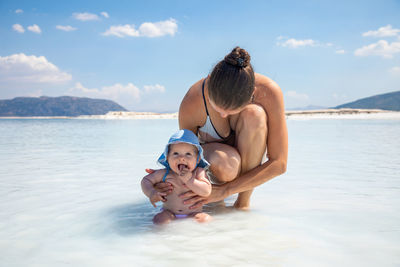 Rear view of mother and daughter in sea against sky