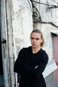 Portrait of young man standing with arms crossed