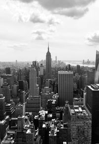 Aerial view of buildings in city against cloudy sky