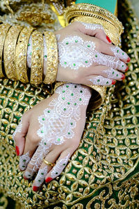 Midsection of woman with heena tattoo on hands