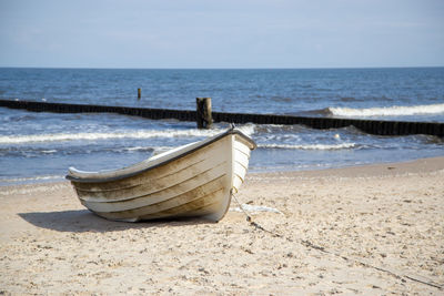 Deck chairs on beach against sky