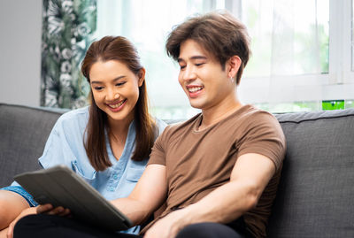 Friends using laptop while sitting on sofa at home