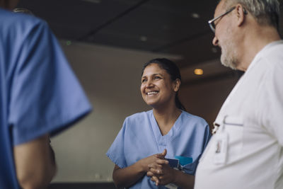 Happy female doctor talking with colleagues in hospital
