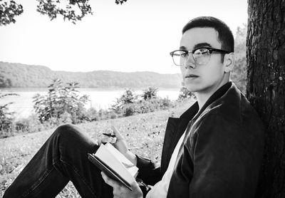 Portrait of young man in eyeglasses sitting outdoors