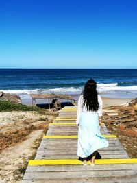 Rear view of woman at beach against clear sky