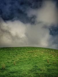 Scenic view of grassy field against cloudy sky