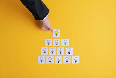 Midsection of man holding yellow paper against orange background