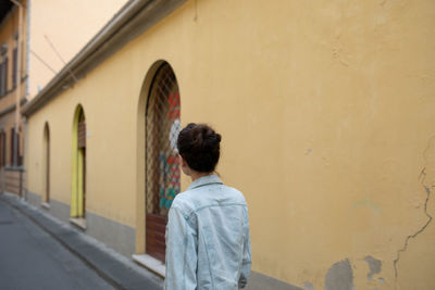 Rear view of woman walking through alley 