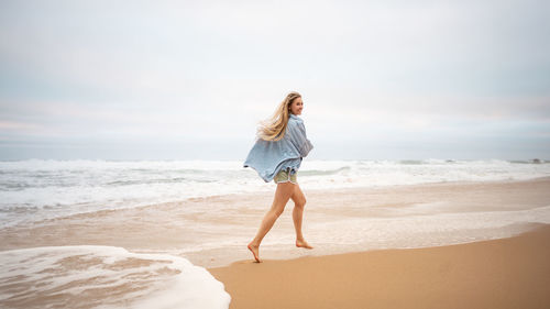 Full length of young woman standing at beach