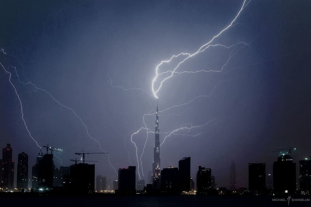 building exterior, night, city, architecture, illuminated, built structure, lightning, sky, cityscape, thunderstorm, power in nature, skyscraper, development, urban skyline, tall - high, low angle view, outdoors, storm, no people, dusk