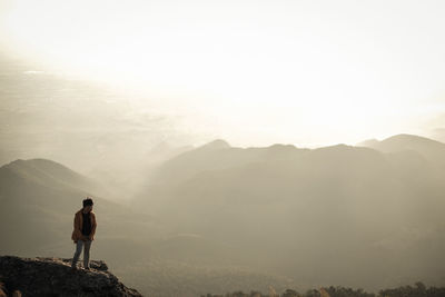 Rear view of man standing on mountain against sky