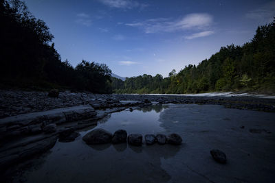 Scenic view of river by trees against sky