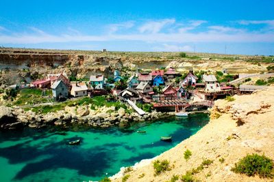 High angle view of houses by river against sky in village on sunny day