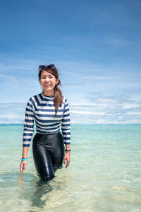 Smiling woman standing at shore against sky