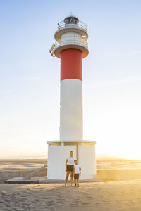 Full length of mother and son standing against light house