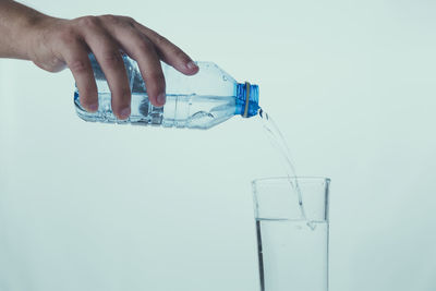 Close-up of hand holding glass of water against white background