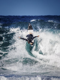 Friends surfboarding in sea against clear sky