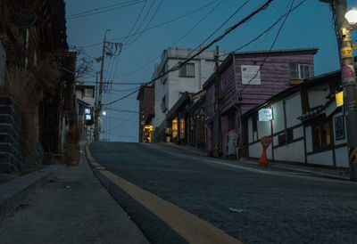 Street amidst buildings in city against sky at dusk