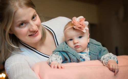 Portrait of smiling mother embracing cute baby girl