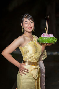 Portrait of young woman standing against wall