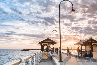 People at beach against sky during sunset