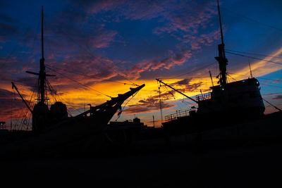 Silhouette sailboats in sea against orange sky