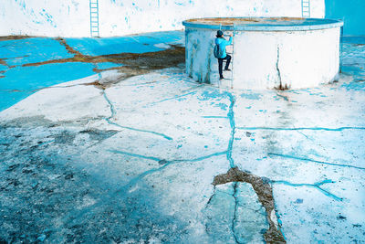 Man climbing stairs on abandoned blue pool