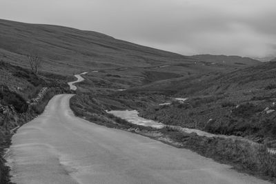 Scenic view of road by mountains against sky