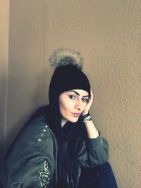 Portrait of young woman standing against wall