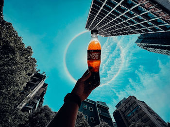 Low angle view of hand holding buildings against sky