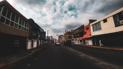 Road amidst buildings in city against sky