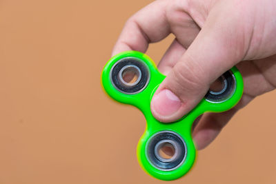 Cropped image of hand holding fidget spinner against brown background