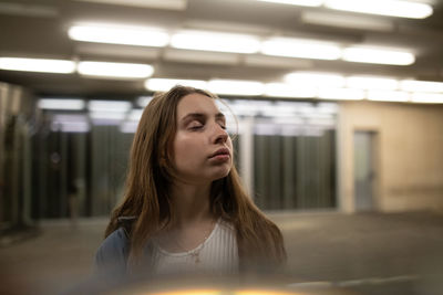 Beautiful young woman with eyes closed in illuminated corridor